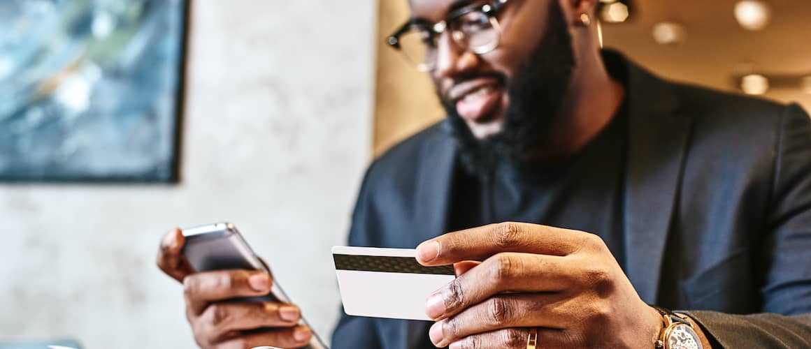man with watch holding credit card and phone