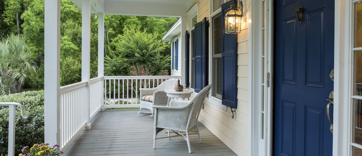 Front porch of a house with blue shutters and front door.