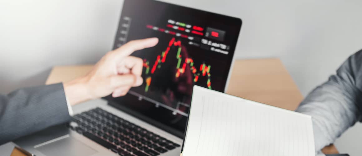 person pointing out stocks on laptop screen
