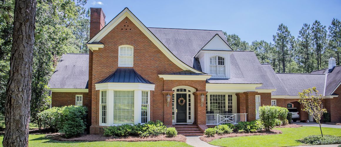 Large house with tree in yard and path up to front door.