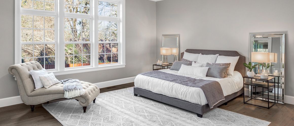 White and grey staged bedroom with large paned windows.