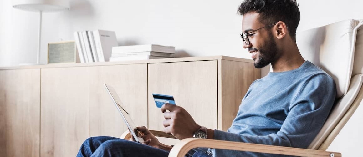 man with glasses holding tablet and credit card