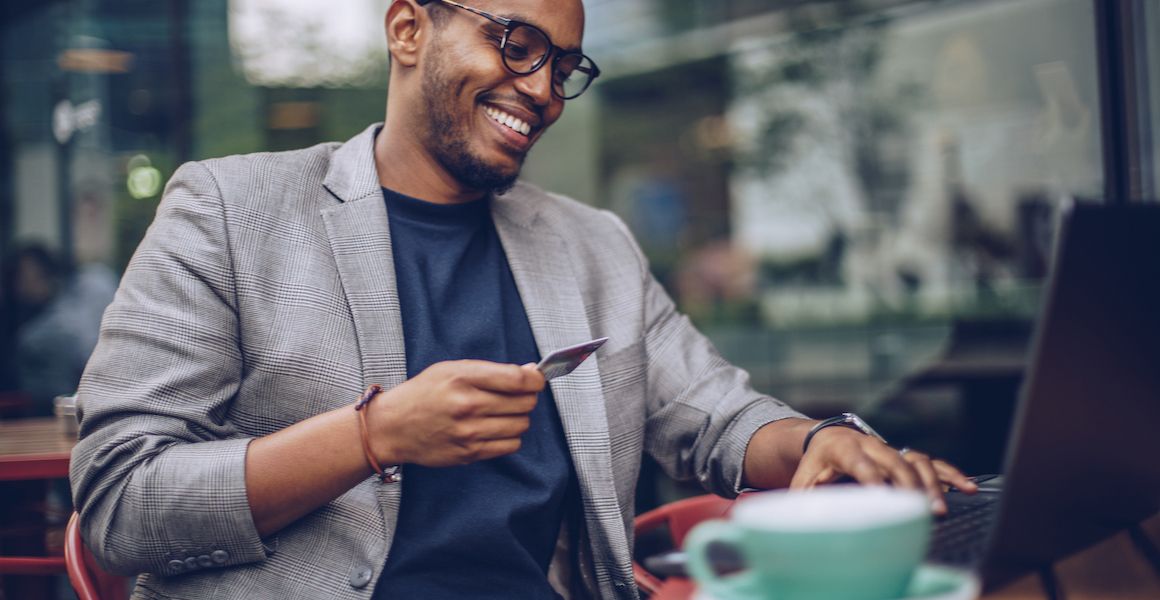 Man holding a credit card at a coffee shop.