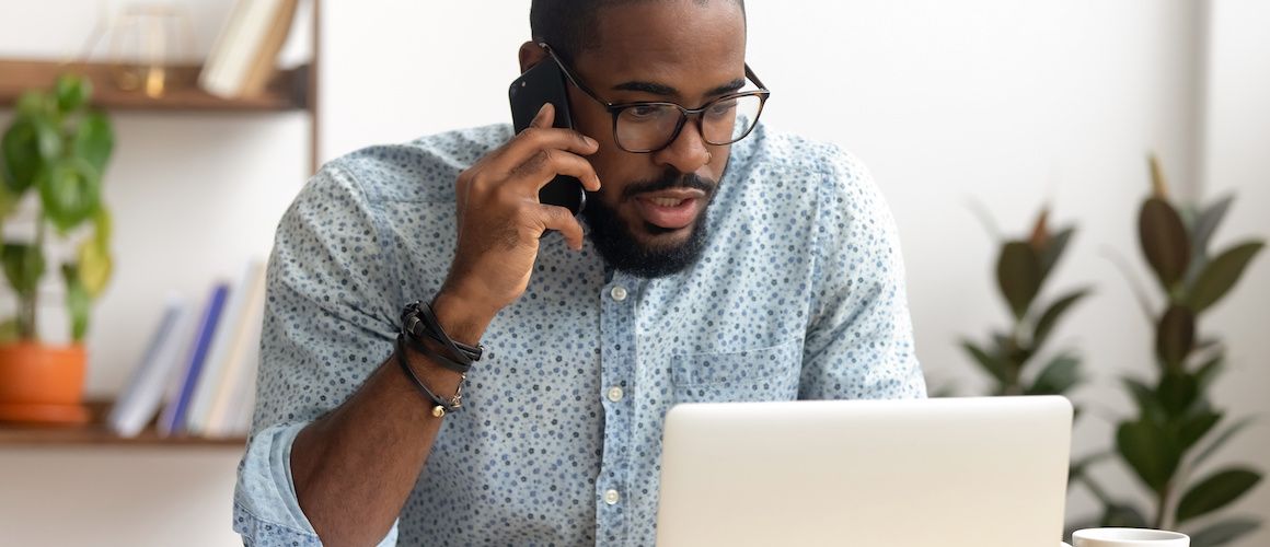 Man on the phone and looking at laptop.