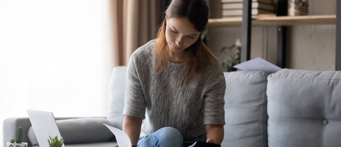 Young woman calculating investments from home.