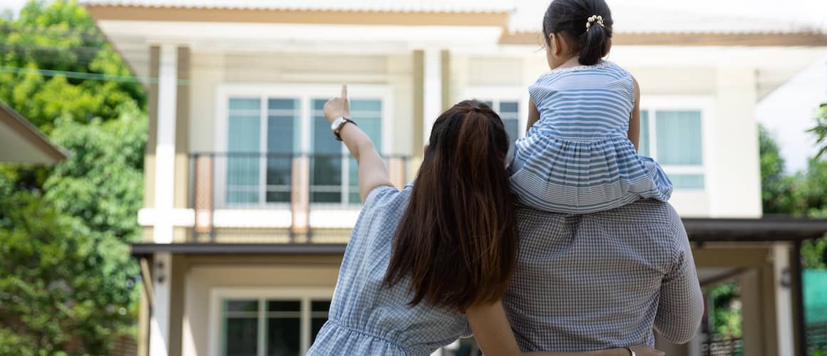 Couple with young child on shoulder of father looking at new home.
