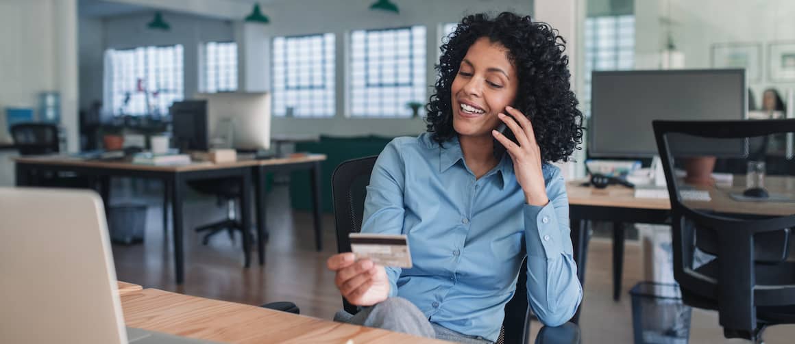 woman on the phone discussing her credit card with her credit card in hand while sitting at desk