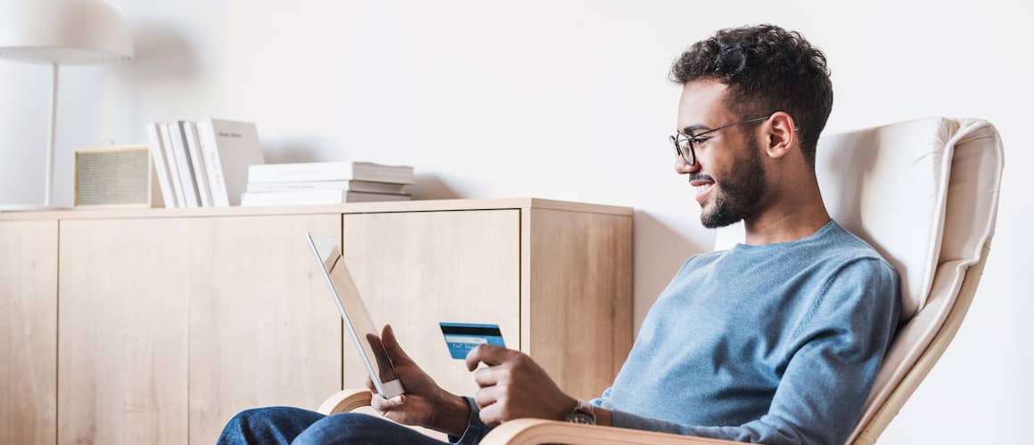 Young Man Using Digital Tablet With Credit Card