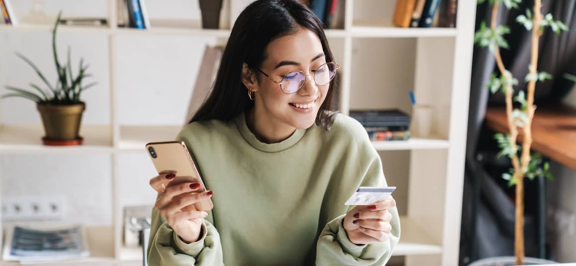 Happy optimistic young girl student holding credit card.