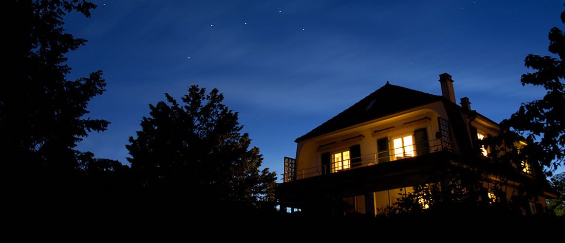 Warmly lit house under a starry night sky.