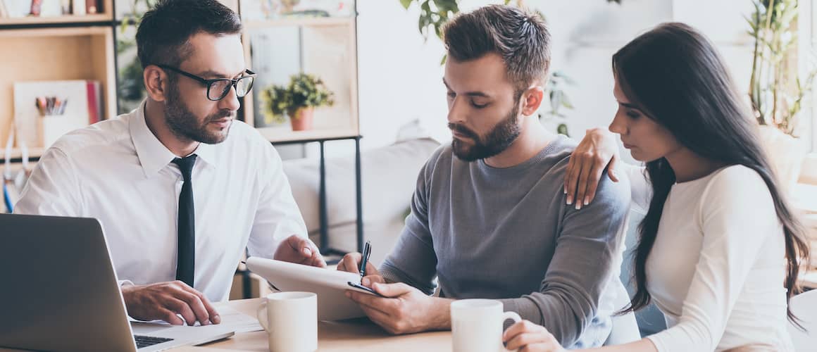 Couple Signing Paperwork With Agent